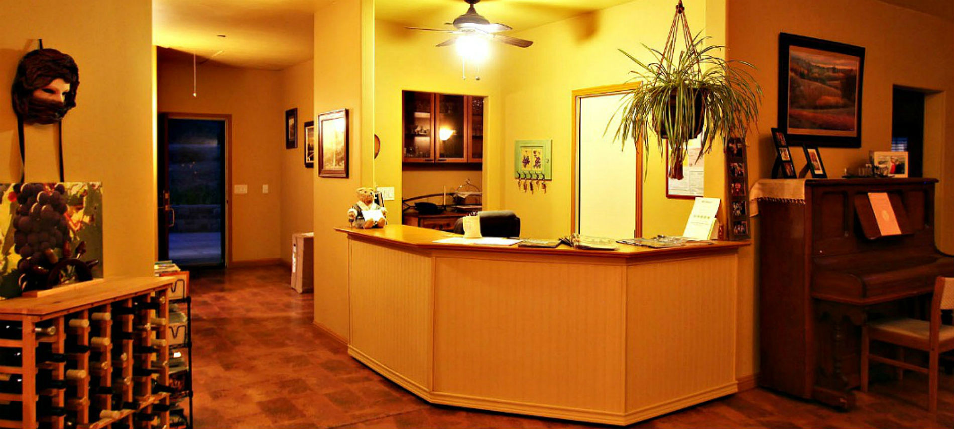 Lucinda’s Reception desk next to the Great Room with the yellow wall and brown floor