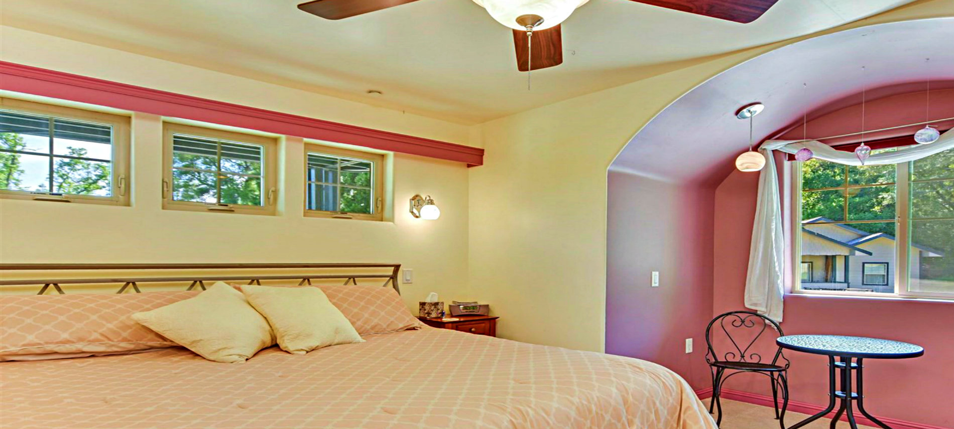 Bed with Tan Spread and Pillows at Head of Bed and a Lace Draping from Ceiling to Corners of Bed