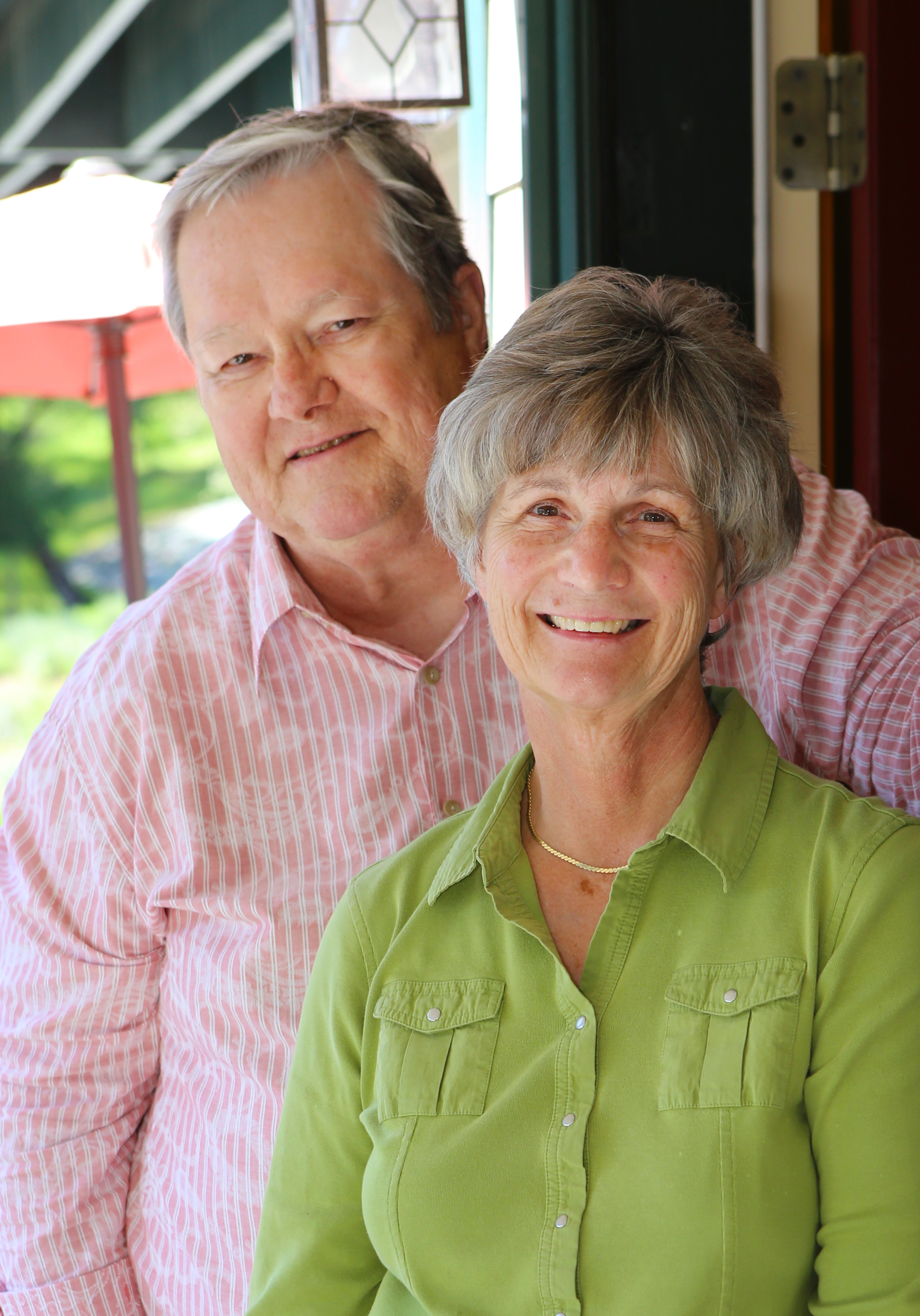 Lucinda and Daryl Sullivan, the Innkeepers, smiling, she in a green blouse, he in a pink and white striped shirt.