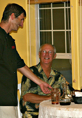 Chef is serving a dinner at a dining table in front of large dining room window.